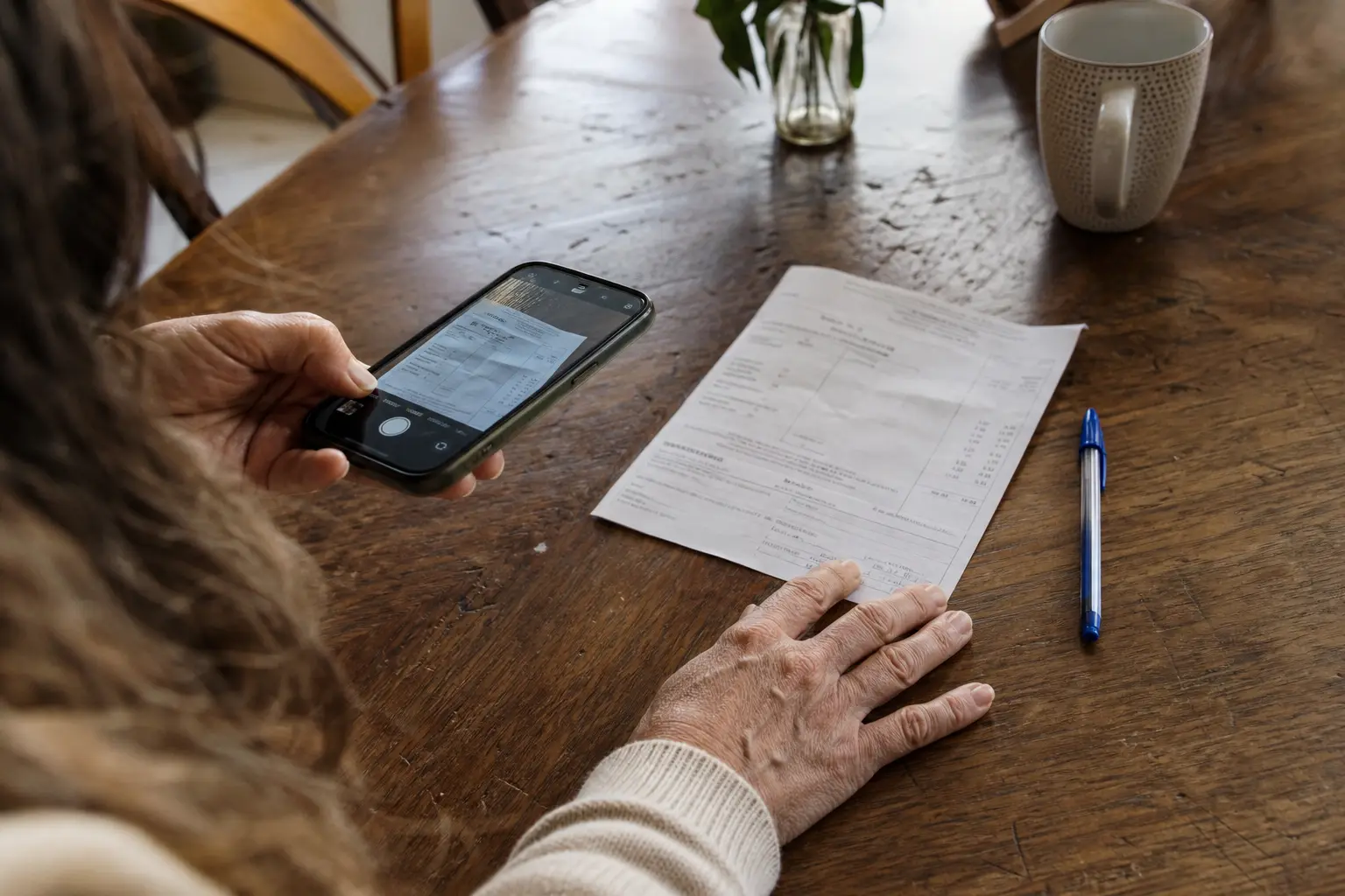 Une facture vétérinaire photographiée avec un téléphone sur une table de cuisine